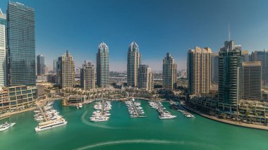 Dubai Marina gökdelenleri gün batımına kadar tüm gün boyunca gökdelenler, lüks yatlar ve marina gezinti güvertesi, Dubai, Birleşik Arap Emirlikleri. Gölge çok hızlı hareket eder. Mavi gökyüzü ve zümrüt su