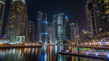 Dubai Yat Limanı defne yatların bir tekne timelapse hyperlapse. En yüksek gökdelenler gece ışıklı kanal suya yansıyan