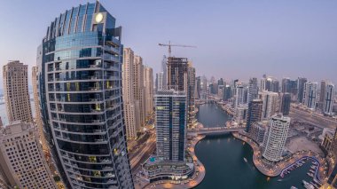 Dubai Marina gezinti güvertesi ve kanalı, gün batımından sonra Dubai, BAE 'de yüzen yat ve teknelerle panoramik hava manzaralı. Modern kuleler ve yoldaki trafik.