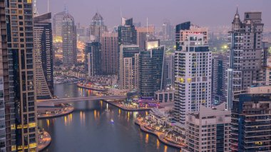 Gün batımından sonra Dubai, BAE 'de yüzen yatlar ve teknelerle Dubai Marina gezinti ve kanallarının hava üzerinden gece gündüz geçiş zamanı. Modern kuleler ve yoldaki trafik.