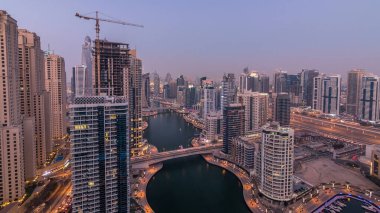 Günden geceye güzel bir hava manzarası. Dubai, BAE 'de gün batımından sonra yüzen yatları ve tekneleri olan Dubai Marina gezinti ve kanallarının panoraması. Modern kuleler ve yoldaki trafik.