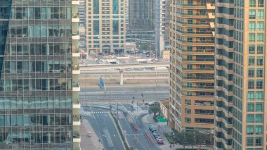 Gün batımında inanılmaz renkli Dubai marinası silueti. Çok uzun gökdelenlerin ve kavşaktaki trafiğin harika perspektifi. Binaların üzerinde güneş ışığı. Birleşik Arap Emirlikleri.