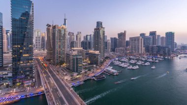 Dubai, BAE 'de gün batımından sonra yüzen yat ve teknelerle Dubai Marina gezinti güvertesi ve kanalı üzerinden geçen güzel bir gökyüzü çizgisi. Modern kuleler ve köprüdeki trafik.