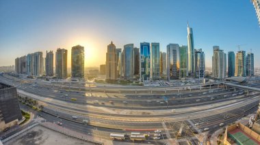 Jumeirah göl kulelerinin gökdelenleri gün doğumunda Şeyh zayed yolunda ve metro hattında trafik varken. Dubai marinasından çatı manzarası
