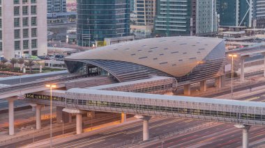 Jumeirah göl kulelerinin hava görüntüsü. Gece gündüz yaya köprüsü geçiş zamanı. Şeyh zayed yolunda ve metro hattında trafik var. Dubai marinasından güneş doğmadan önce çatı manzarası
