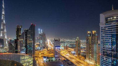 En yüksek bina ve Sheikh Zayed karayolu trafik, Birleşik Arap Emirlikleri Dubai şehir manzarası gece timelapse. Işıklı modern kuleli gökdelenin çatı üzerinden havadan görünümü