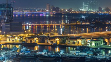 Dubai deresi gece manzarası limanda tekneler ve yatlar ve köprüde trafik olan modern binalar. İnşaat alanı yukarıdan gökyüzü görüntüsü