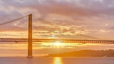Lisbon city sunrise with April 25 bridge timelapse, River and waterfront early morning. Orange clouds on the sky