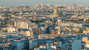 Paris 'teki evlerin çatılarının üstündeki hava manzarası. Günbatımından önce altın kubbe ve uzun gölgelerle akşam manzarası