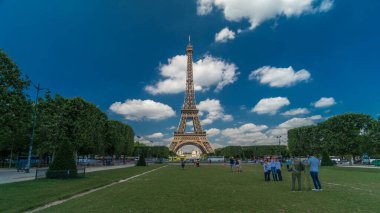 Paris 'teki Champs de Mars' taki Eyfel Kulesi. Zaman atlaması, Fransa. Yazın mavi bulutlu gökyüzü Yeşil çimlerle ve insanlar etrafta yürüyüp rahatlıyorlar
