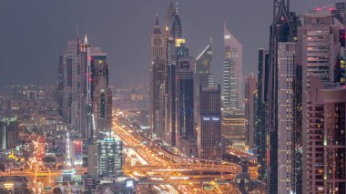 Dubai şehir merkezinde gökdelenler ve Gece geçiş timelapse, Dubai, Birleşik Arap Emirlikleri Şeyh Zayed yol gün havadan görünümü. Modern kuleler ve karayolu üzerinde akşam trafiği