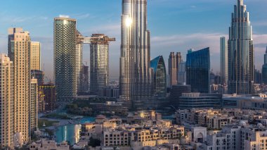 Dubai Şehir Merkezi 'nin ufuk çizgisi, güneş doğarken Burj Halife ve Dubai' deki diğer panoramik kulelerle birleşik Arap Emirlikleri. Gökdelenin cam yüzeyinden yansıyan güneş