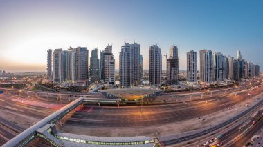 Dubai Marina 'dan Sheikh Zayed yoluna gece gündüz aydınlık gökdelenler ile hava panoramik görüntüsü, geçiş zamanı, Dubai. Trafik, köprüler ve metro istasyonu. Birleşik Arap Emirlikleri