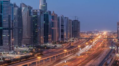 Dubai Marina 'dan Şeyh Zayed yoluna gece gündüz aydınlık gökdelenlerle geçiş zamanı, Dubai. Trafik, köprüler ve metro istasyonu. Birleşik Arap Emirlikleri
