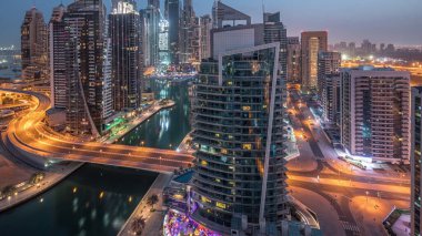 Dubai Marina yerleşim yerlerinin ve ofis gökdelenlerinin hava panoramik görüntüsü. Köprü ve rıhtımda gece gündüz trafik var. Gün doğumundan önce geçiş zamanı. Yüzen tekneler ve yatlar
