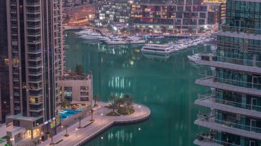 Dubai Marina 'daki rıhtım güvertesi gece gündüz geçiş zamanı. Kanalda yüzen tekne ve yatlar. Dubai, Birleşik Arap Emirlikleri