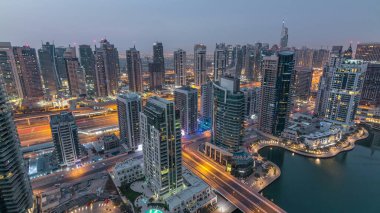 Dubai Marina gece gündüz geçiş timelapse havadan üst görünümü. Dubai, Bae gün doğumundan önce yüzen yatlar ve tekneler ile gezinti ve kanal. Işıklı modern kuleler ve yolda trafik