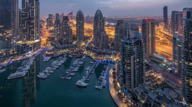 Dubai Marina gece gündüz geçiş timelapse havadan üst görünümü. Dubai, Bae gün doğumundan önce yüzen yatlar ve tekneler ile gezinti ve kanal. Işıklı modern kuleler ve yolda trafik