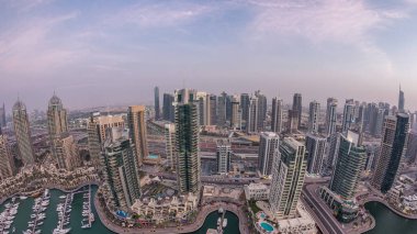 Dubai Marina'nın havadan üstten gündüz geceye geçiş saati. Dubai, Bae gün batımından sonra yüzen yatlar ve tekneler ile gezinti ve kanal. Işıklı modern kuleler ve yolda trafik