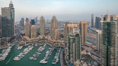 Dubai Marina'nın havadan üstten gündüz geceye geçiş saati. Dubai, Bae gün batımından sonra yüzen yatlar ve tekneler ile gezinti ve kanal. Işıklı modern kuleler ve yolda trafik