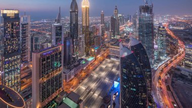 Sheikh Zayed Yolu yakınlarındaki binaların silueti ve Dubai, BAE 'deki hava gününden geceye geçiş. Günbatımından sonra finans merkezinde ve şehir merkezinde park yeri olan modern kuleler ve gökdelenler.