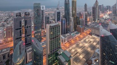 Sheikh Zayed Yolu yakınlarındaki binaların silueti ve Dubai, BAE 'deki hava trafiği gece gündüz değişiyor. Gündoğumundan önce finans merkezinde ve şehir merkezinde modern kuleler ve aydınlık gökdelenler