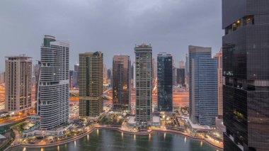 Jumeirah gölükuleleri konut ve ofis binaları Dubai'de gün doğumundan önce gündüz geçiş timelapse ilçe gece. Işıklı modern gökdelenler ile yukarıdan havadan panoramik görünüm