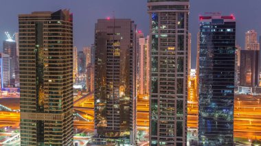 Jumeirah gölükuleleri konut ve ofis binaları Dubai'de gün doğumundan önce gündüz geçiş timelapse ilçe gece. Işıklı modern gökdelenler ile yukarıdan havadan panoramik görünüm