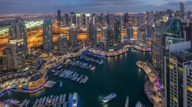 Dubai Marina gökdelenleri ve Jumeirah göl kuleleri Birleşik Arap Emirlikleri 'nde hava gününden geceye geçiş zamanlarını gösteriyor. Yolda trafik ve yüzen yatlar.