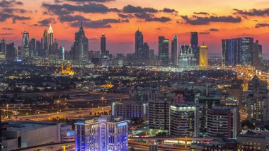 Şehir merkezinde büyük gökdelenler ve onlardan gelen ışıklar ve renkli gökyüzü, Dubai, Birleşik Arap Emirlikleri ile finans bölgesi Timelapse 'nin havadan görünüşü