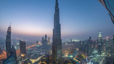 Şehir merkezindeki Dubai 'nin panoramik gökyüzü manzarası. Alışveriş merkezi, çeşmeler ve Burj Khalifa hava gece gündüz geçiş zamanı. Gündoğumundan önce modern gökdelenler ve bulutlu gökyüzü