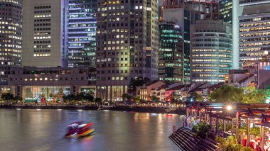 Singapur rıhtımı merkezi iş bölgesinde uzun gökdelenler ve Boat Quay 'de küçük restoranlar gün batımından sonra geçiş zamanı.