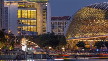 Alacakaranlıkta Singapur Körfezi 'ndeki Esplanade Tiyatrosu' nda. Gündüzden geceye geçiş zamanlarında çok güzel bir yansıması var. Merlion Park 'taki insanlar