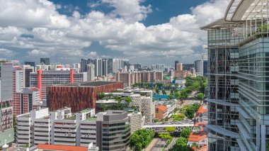 Singapur silueti Victoria caddesi ve Ulusal Kütüphane havadan zaman aralığı hipervanesi. Trafiği olan yeşil ağaçlar. Mavi gökyüzünde bulutlar