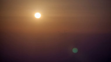 Abu Dabi şehrinin ufuk çizgisi, gün doğumunda inşaat ve vinçlerle dolu. Çatıdan sisli bir sabahta hava manzarası