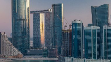 Abu Dabi 'deki Al Reem Adası' ndaki binalar yukarıdan zaman çizelgesi. Al Reem Adası 'nın akşamları gökdelenlerdeki yansımasını gösteren hava manzarası.