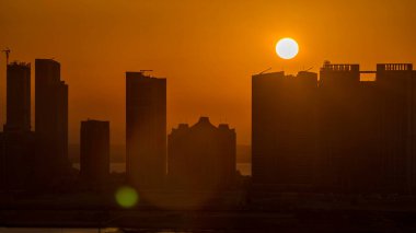 Al Reem 'deki gökdelenler ve Abu Dabi' deki Al Maryah Adası 'ndaki günbatımında gökdelenler. Al Reem Adası 'ndan modern binaların siluetleri olan havadan şehir manzarası. Turuncu gökyüzü