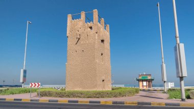 Ajman zaman kulesinin mavi gökyüzü ve yoldaki trafik hızını izleyin. Birleşik Arap Emirlikleri