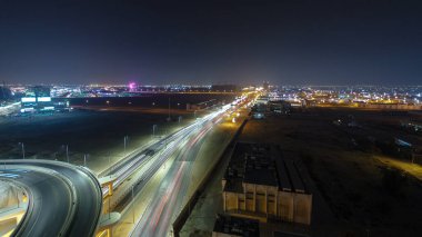Panorama, Ajman hava sahasında büyük bir kavşakta trafiği gösteriyor. Gece vakti çatıdan görünüyor. Birleşik Arap Emirlikleri 'nde üst geçitle kesişen birçok araba var..