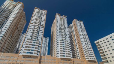Ajman zaman ayarlı hiperhızlandırılmış modern yeni kuleler. Ajman 'ın yerleşim yeri ve ofis gökdelenleri olan şehir manzarası. Mavi gökyüzü. Birleşik Arap Emirlikleri.