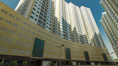 Ajman zaman ayarlı hiperhızlandırılmış modern yeni kuleler. Ajman 'ın şehir manzarası. Yerleşim yerleri ve ofis gökdelenlerinde gölgeler var. Birleşik Arap Emirlikleri.
