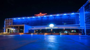 Aktau 'nun otel ve restoranlı gece hiperlapası. Aydınlatılmış Binalar Kazakistan 'ın Canlı Yüreğinde Akşam Gökyüzünü aydınlatıyor