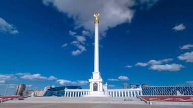 Kazakistan 'ın başkenti Astana' daki Independence Meydanı 'ndaki Kazak Eli Anıtı' nın zaman atlaması görüntüsü. Alttaki çiçek tarhında. Yaz günü mavi bulutlu bir gökyüzü. Nur-Sultan şehri