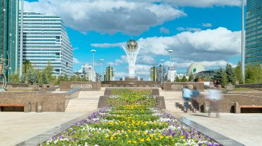 Nurzhol Bulvarı 'nda çiçekler. Arka planda Baiterek var. Kazakistan 'ın başkenti Nur-Sultan' da bir anıt, şehrin en önemli yerlerinden biri. Yazın mavi bulutlu gökyüzü