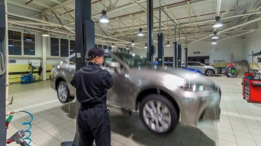Araba tamircisi vidaları söküyor ve tamir istasyonunda pnömatik ingiliz anahtarıyla kaldırılan otomobilin vidalarını söküyor. Tramvayda tekerlekleri hareket ettirir