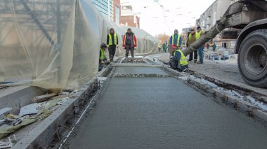 Çelik takviyesi yaptıktan sonra beton karıştırıcı zaman aşımına uğrayarak yolu hızlandırmak için hazır beton dökülüyor. Çadırla kaplı yeni raylar. Tramvay raylarının yeniden inşası