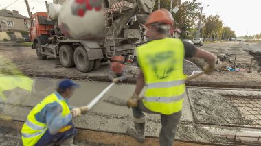 Beton işleri ve yol inşaatı için bir sürü işçi ve mikser hızlandırıcı ile aynı seviyeye gelmek. Metal takviyesine harç dökülüyor. Tramvay raylarının yeniden inşası