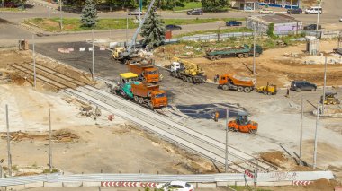 Asfalt kaldırım taşı, paten ve kamyon asfaltlama sırasında yol onarım alanında. Tramvay raylarının havadan görünüşü. Yol yapım ekipmanları. Yol ayrımında inşaat işçileri.