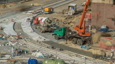 Concrete works for road construction with many workers in uniform and mixer machine and crane timelapse. Reconstruction of tram tracks