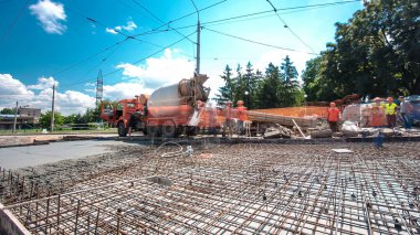 Tramvay rayları onarılan ve bakım süreleri yüksek olan yol inşaatı. Metal bir şebekede mikserden beton dökülüyor. Kavşağın ortası..